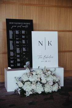 white flowers are on display in front of a black and white sign that says n k