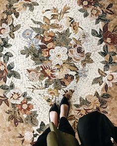 a woman's feet on the ground with a mosaic design