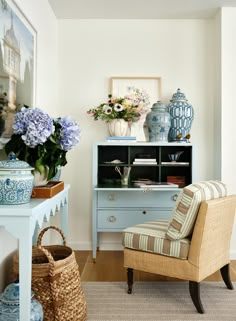 a blue and white chair sitting next to a table with vases on top of it