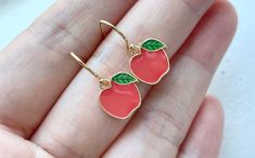 These red / green apple earrings are dainty and kawaii. They are made of the followings: (1) Gold plated enamel apple charm (10 x 11 mm) (2) Gold plated or 14KGF earring hooks ✏️ Please choose your desired color of apple charm ✏️ Please choose your desired plating of earring hooks 🍎 NECKLACE 🍏 → https://www.etsy.com/listing/1026344723 【BEFORE PURCHASE, PLEASE NOTE THE FOLLOWINGS】 ☆ VAT, GST and any other taxes from your country are NOT included in the listing price. Buyers are responsible for Cute Red Round Jewelry, Cute Round Red Jewelry, Cute Cherry-colored Jewelry For Gifts, Cute Cherry-colored Jewelry Gift, Handmade Red Kawaii Jewelry, Cute Red Enamel Earrings, Cute Red Earrings With Fruit Design, Cute Fruit Design Jewelry For Gifts, Cute Fruit Design Jewelry As Gift