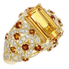 This One of a Kind Juleve Precious Topaz, Citrine, & Diamond Floral Design Ring. The Ring is Crafted in 14 Karat Yellow Gold & Features a 4.09 Carat Center Emerald Cut Precious Topaz. The Center Precious Topaz is accompanied by a Floral Design of Round Citrines that Weigh 0.65 Carats total Weight & 0.79 Carats of round Diamonds. Yellow Topaz Jewelry, Fine Jewelry Yellow Topaz Ring, Luxury Citrine Topaz Ring With Gemstone Accents, Luxury Yellow Topaz Ring With Diamond Accents, Luxury Citrine Topaz Ring Fine Jewelry, Luxury Yellow Topaz Jewelry, Sweet Jewelry, Round Diamond Setting, Imperial Topaz