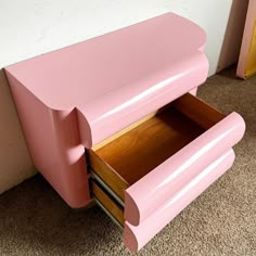 a pink wooden cabinet with two drawers on the bottom and one drawer open to show what's inside