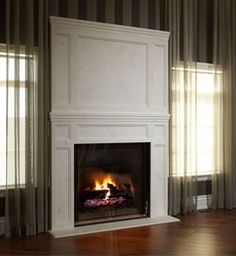 a fire place in the middle of a room with curtains on either side and sunlight streaming through the windows