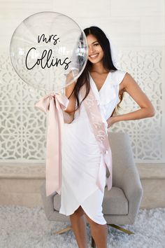 a woman in a white dress holding a clear balloon with the words mrs collins on it