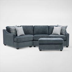 a blue sectional couch and ottoman with pillows