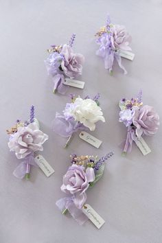 purple and white flowers are arranged in rows on a gray tablecloth with name tags