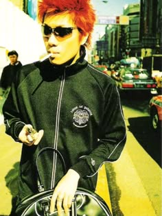 a man with red hair wearing sunglasses and carrying a bag