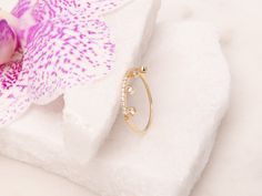 a pink flower sitting on top of a white piece of paper next to a gold ring