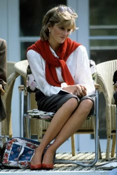 a woman sitting in a chair wearing a red scarf