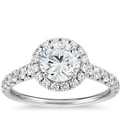 a white gold engagement ring with an oval center surrounded by round diamonds