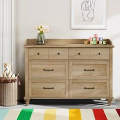 a baby's room with a wooden dresser and colorful rug