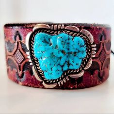 An exquisite sterling turquoise brooch handmade by Navajo artisan L. Smith features a rugged chunk of brilliant blue Kingman turquoise surrounded by a carved platform of sterling silver and paired with a spectacular vintage hand tooled leather belt to be repurposed into a leather bracelet. A deerskin lace wraps around a genuine Indian Head buffalo nickel concho for a comfortable, secure and adjustable tie-on closure. Western Hand Tooled Cuff Bracelet As Gift, Artisan Concho Cuff Bracelet As Gift, Artisan Cuff Bracelet With Concho As Gift, Southwestern Concho Cuff Bracelet Gift, Vintage Leather Jewelry With Concho, Vintage Leather Jewelry With Patina, Rustic Leather Stamped Jewelry, Rustic Hand Tooled Leather Jewelry, Vintage Brown Jewelry For Western-themed Events