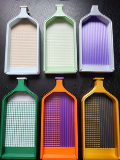 four different colored graters sitting next to each other on top of a table