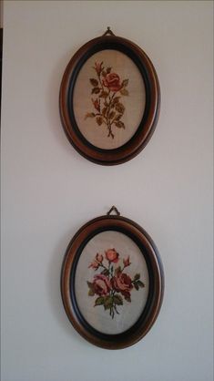 two cross stitch roses are hanging on the wall next to each other in wooden frames