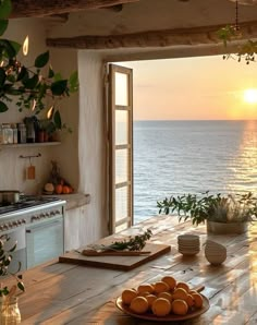 a table with oranges on it in front of an open window overlooking the ocean