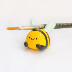 a yellow and black toy with a smile on it's face next to a brush