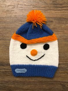 a knitted snowman hat with an orange and blue pom - pom