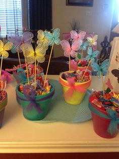 there are many colorful cupcakes in the cups on the table with candy sticks sticking out of them