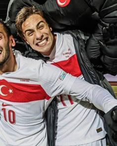 two men are hugging each other while wearing soccer uniforms