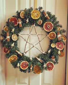 a wreath made out of oranges and cinnamon sticks is hanging on the front door