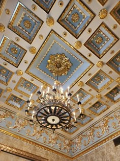 a chandelier hanging from the ceiling in a room with gold and blue tiles