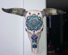 a bull's skull with long horns decorated with blue and green designs on it