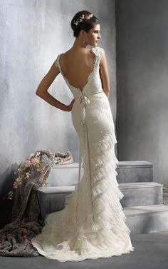 a woman in a wedding dress standing on some steps with her back to the camera