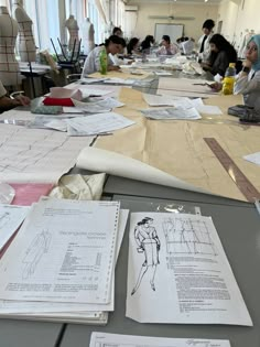 many people are sitting at a table with paper work on it and papers spread across the table