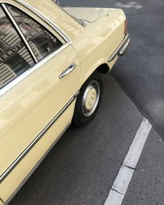 an old yellow car parked on the side of the road