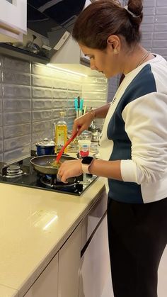 a woman is cooking on the stove in the kitchen with her utensils sticking out