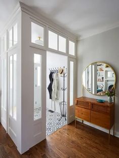 an entry way with a mirror and coat rack on the wall in front of it