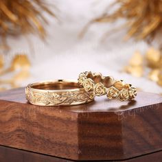 two gold wedding rings sitting on top of a wooden box