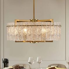 a chandelier hanging over a dining table with wine glasses and plates on it