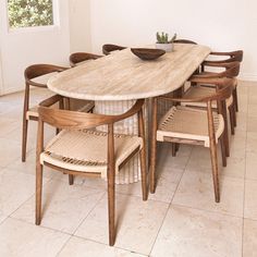 a dining room table with six chairs and a bowl on top of it, in front of a window