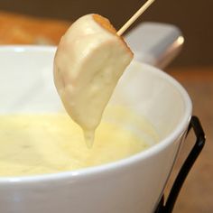 a white bowl filled with soup and an appetizer on a stick sticking out of it