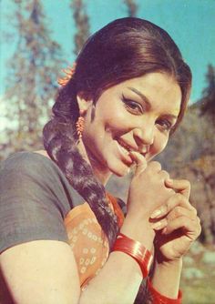 an old photo of a woman smiling and holding her hand up to her face, with trees in the background