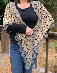 a woman standing on a deck wearing a crocheted shawl