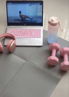 a laptop computer sitting on top of a table next to dumbs and headphones