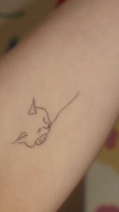 a small tattoo on the arm of a woman with a cat's head drawn on it