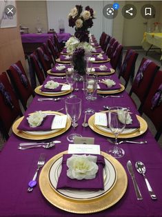 the table is set with purple linens and gold place settings, along with silverware