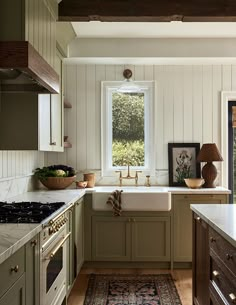 a kitchen with an oven, sink and window in the center is decorated in green