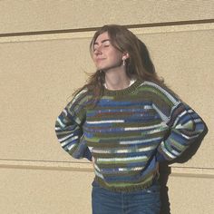 a woman standing in front of a wall with her hands on her hips and looking up