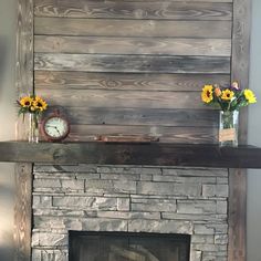 a fire place with flowers and a clock on the mantle