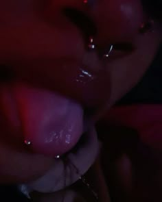 a close up of a person with piercings on their nose and tongue in the dark