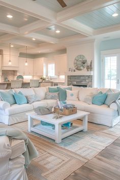 a living room filled with white furniture and blue pillows on top of it's couches