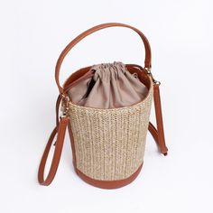 Made from high quality Raffia. Vegan leather trim. Polyester lining. Our raffia line are all made with an interior liner to keep your items safe and enclosed from beach sand or any harsh environment. Great size for traveling and for the summer heat.  Detachable shoulder strap included. Dimensions: 150x215X150mm Weight:  286g (bag) SHIPPING:  Free shipping from South Korea, estimated 7-14 days to get to you from purchase date.  RETURNS:  Return address is in USA so that returns can be made and given fast.  Returns up to 2 weeks starting when the shipping is completed.  Returns must be with tags.  Buyer must pay for return shipping unless item was damaged or incorrect.  Money will be refunded after we receive and inspect the item. Orders over $250 will have to pay 20% restocking fee. Beige Woven Leather Bucket Bag, Casual Woven Bucket Beach Bag, Casual Bucket-shape Straw Bag With Leather Handles, Casual Straw Bag With Leather Handles In Bucket Shape, Casual Straw Bag With Leather Handles And Bucket Shape, Natural Woven Leather Bucket Bag, Brown Bucket Straw Bag For Beach Season, Brown Bucket Beach Bag For Vacation, Straw Bucket Bag For Travel