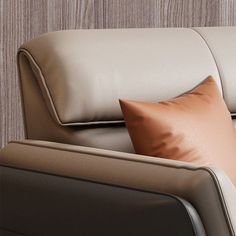 a close up of a couch with pillows on the armrests and a wooden wall behind it