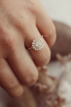 a woman's hand with a diamond ring on top of her finger and the other hand holding it