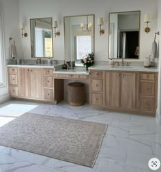 a large bathroom with double sinks, mirrors and rugs on the floor in front of two windows