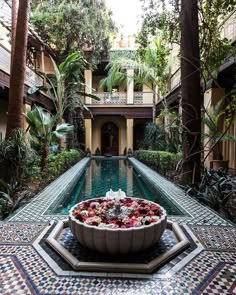 a bowl filled with flowers sitting on top of a tiled floor next to a pool